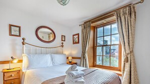 A hotel room with a bed, bedside tables, a window with curtains, a mirror, and framed pictures on the wall. - 1 Bed in Keswick (oc-sz472) (Keswick)
