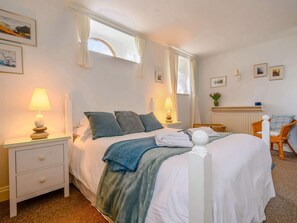A well-lit bedroom with a bed, two bedside tables, a chair, and a window with curtains. - 3 Bed in Penrith (oc-sz318) (Ullswater)