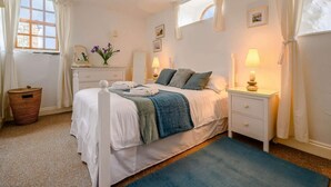 Ein Schlafzimmer mit Bett, Nachttischen, einem Schminktisch und einem Spiegel.
