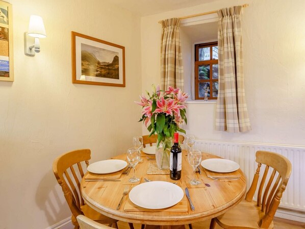 A dining table set for four with a vase of flowers, wine glasses, and plates. - 2 Bed in Penrith (oc-sz339) (Ullswater)