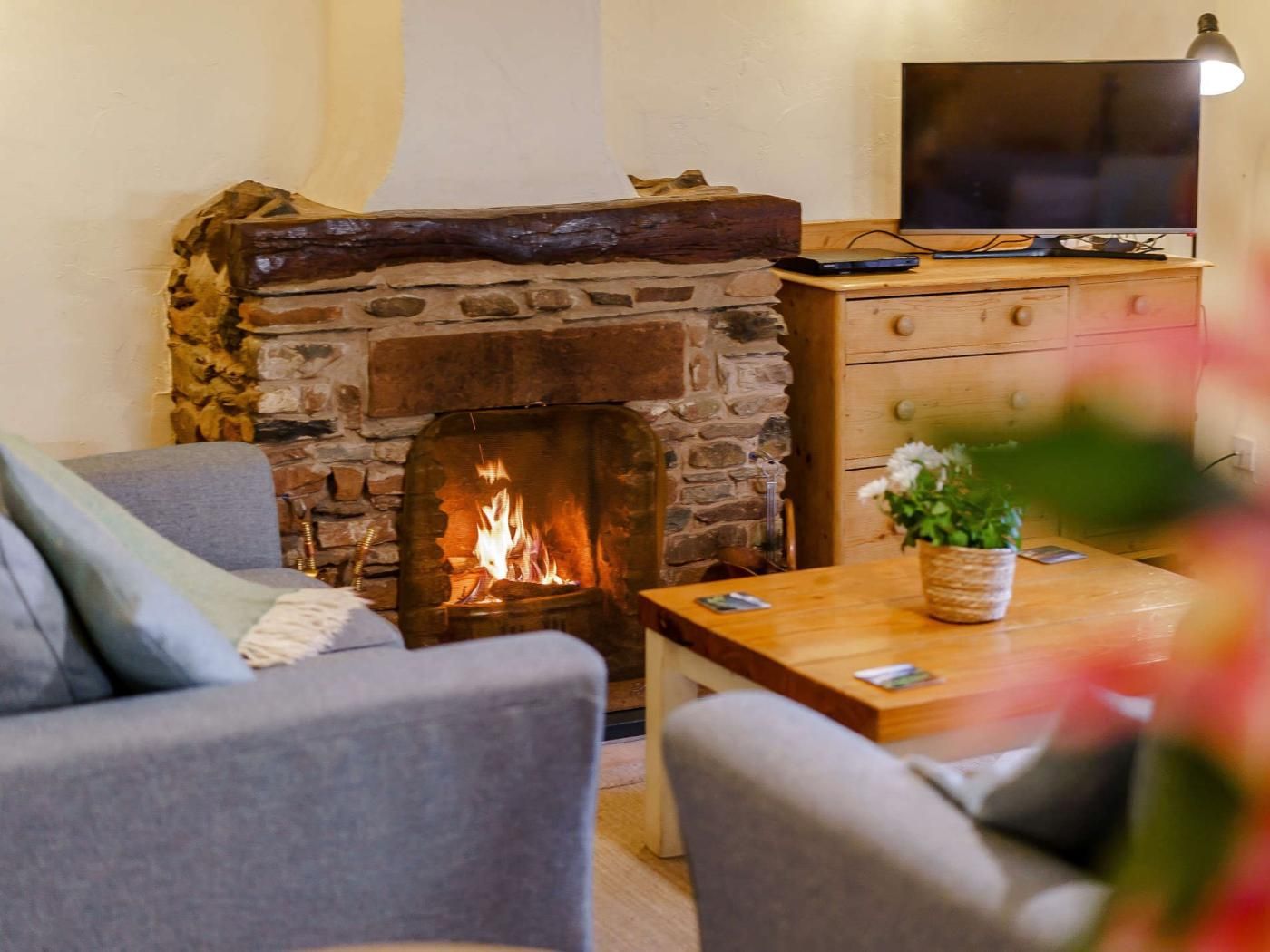 A cozy living room with a stone fireplace, a television on a wooden stand, and a sofa.