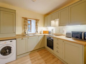 A compact kitchen with a washing machine, a microwave, and a toaster. - 2 Bed in Penrith (oc-sz339) (Ullswater)