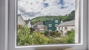 Uitzicht vanuit een raam op een woongebied met huizen, een heuvel en een heldere lucht.