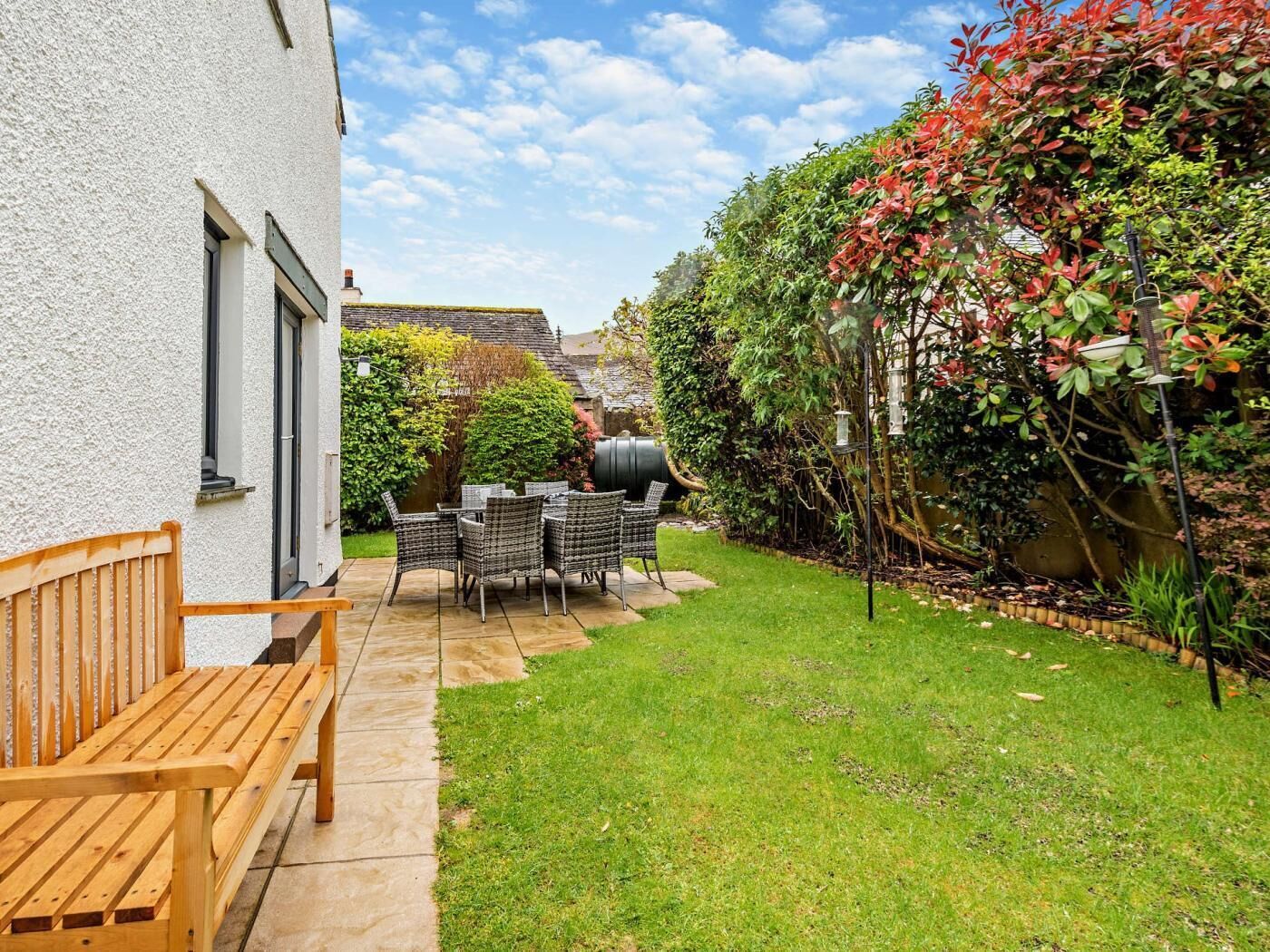 Une terrasse avec des meubles d’extérieur, une pelouse et un bâtiment blanc doté de fenêtres.