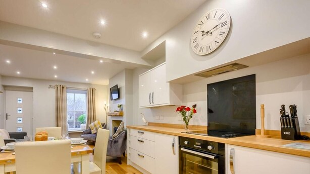 A modern kitchen with a large wall clock, wooden countertops, and built-in appliances. - 2 Bed in Keswick (oc-sz036) (Keswick)