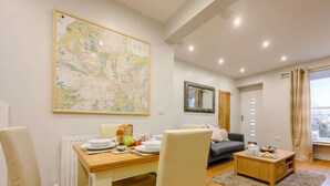 A dining area with a table set for two, a sofa, and a large map on the wall. - 2 Bed in Keswick (oc-sz036) (Keswick)