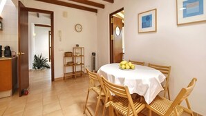A dining area with a round table, wooden chairs, a white tablecloth, and a ceiling light fixture. - Villa in Son Servera With Private Pool & Beaches (Son Servera)