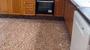 Een keuken met houten kastjes, een magnetron, een broodrooster, een oven en een vaatwasser.