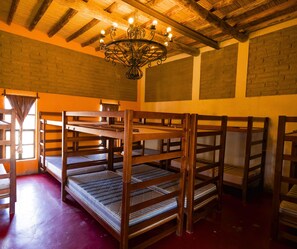 Bunk beds arranged in a room with brick walls, a wooden ceiling, and a chandelier.