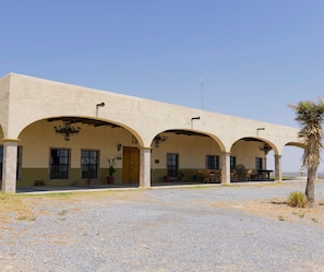 A building with a flat roof, multiple arches, and a gravel ground.