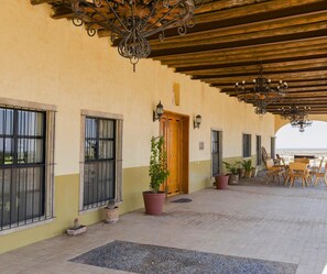 A covered outdoor area with a wooden ceiling, potted plants, and a view of the sea.