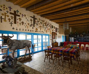 Une pièce avec un plafond en bois, une statue de taureau, une machine à coudre et un mur orné de croix.