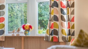 A room with a window, a radiator, a white table, and a cushion. - 2 Bed in Ravenglass (oc-sz514) (Ravenglass)