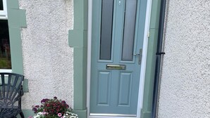 A door with a sign reading 'The Retreat,' a black metal lantern, and a chair outside. - 2 Bed in Ravenglass (oc-sz514) (Ravenglass)
