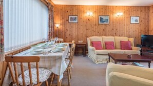 A dining area with a table set for four, a sofa, a television, and framed pictures on the wall. - 2 Bed in Cockermouth (oc-sz164) (Mockerkin)