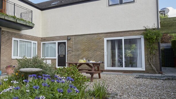 A two-story house with a patio, a wooden table, and a garden with flowers. - 2 Bed in Cockermouth (oc-sz164) (Mockerkin)