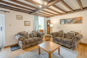 A living room with two patterned sofas, a wooden coffee table, a clock, and a mirror on the wall. - 2 Bed in Penrith (oc-sz276) (Stainton)