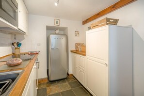 Una cocina con un refrigerador de acero inoxidable, un microondas y una encimera de madera.