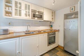 A kitchen with white cabinets, a stainless steel oven, a microwave, a sink, and a refrigerator. - 2 Bed in Penrith (oc-sz276) (Stainton)