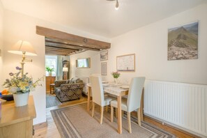 Une pièce chaleureuse comprenant une table à manger, des chaises, un canapé, une lampe et un radiateur.