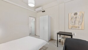A bedroom with a bed, a desk, a chair, a wardrobe, and a painting on the wall. - Barrio Sanctuary - Nova (San Juan)