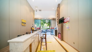 Une cuisine moderne avec un plan de travail en marbre, des tabourets en bois et une vue sur la rue.