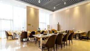 Une salle de conférence équipée de tables et de chaises, de grandes fenêtres et d’une horloge au mur.