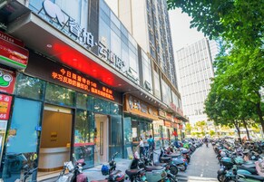 Vista de la calle con una fila de scooters estacionados, un edificio con un letrero en idioma extranjero y un edificio alto al fondo.