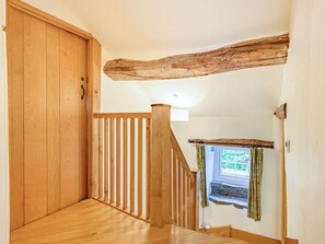 Eine HolztTreppe mit Geländer, eine Holztür und ein Fenster mit Vorhängen.