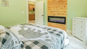 Une chambre à coucher avec un lit, un panneau mural en bois, une cheminée et une commode blanche.