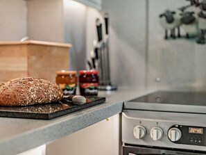 A kitchen counter with a loaf of bread, jars of jam, and a stove. - 2 Bed in Keswick (oc-sz027) (Keswick)