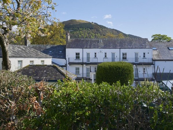 A row of white buildings with a hill in the background. - 2 Bed in Keswick (oc-sz027) (Keswick)
