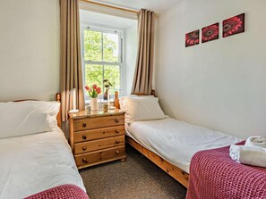 A bedroom with two single beds, a wooden dresser, a window with curtains, and a wall with three framed pictures. - 2 Bed in Keswick (oc-sz027) (Keswick)