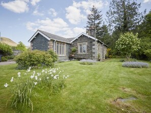 Ein Steinhaus mit gepflegtem Rasen und Garten.