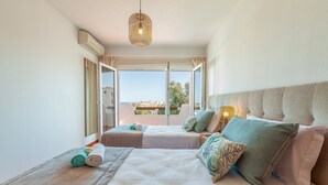Quarto de hotel com duas camas, uma janela grande com vista e um candeeiro de teto.