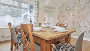 Een eetgedeelte met een houten tafel, stoelen en een kaart aan de muur.