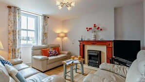 A living room with a sofa, a coffee table, a fireplace, and a television.