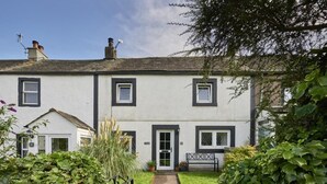 Une maison à deux étages avec une porte d’entrée, des fenêtres et un chemin menant à l’entrée.