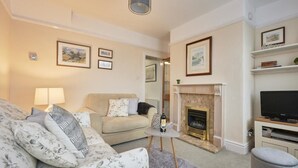 A living room with a sofa, a small table with a bottle, a fireplace, and a television. - 2 Bed in Keswick (oc-sz117) (Keswick)