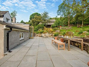 A patio with stone flooring, a wooden bench, and a table with drinks. - 4 Bed in Kendal (oc-sz535) (Kentmere)