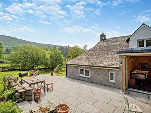 A house with a stone patio, outdoor seating, and a view of green hills. - 4 Bed in Kendal (oc-sz535) (Kentmere)