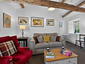 A cozy living room with a red sofa, a grey sofa, a wooden coffee table with a magazine and a board game, and a lamp. - 1 Bed in Carnforth (oc-sz527) (Barbon)