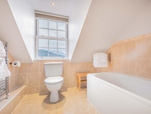 Ein modernes Badezimmer mit Toilette, Badewanne und Fenster.