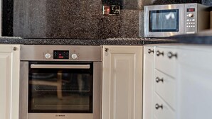 Una cocina con horno Bosch, microondas y un reloj digital.