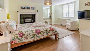 Un dormitorio con cama, chimenea, televisor y ventana.