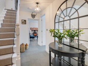 A staircase with beige carpeted steps, a black metal-framed mirror, and a round table with vases. - 3 Bed in Penrith (oc-sz571) (Patterdale)