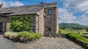 A stone building with a sloped roof, a small window, and a door. - 2 Bed in Ulverston (oc-sz591) (Haverthwaite)