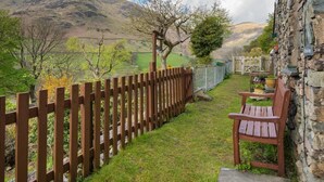 A stone building with a wooden fence, a bench, and a view of a mountain. - 3 Bed in Penrith (oc-sz184) (Glenridding)