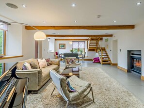 A spacious living area with a sofa, armchair, and a dining table. A staircase leads to an upper level. - 4 Bed in Holmrook (oc-sz293) (Irton with Santon)