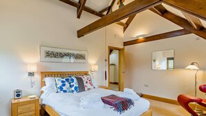 Ein Schlafzimmer mit einem hölzernen Bett, Nachttischen, einem Spiegel und einem roten Sessel.